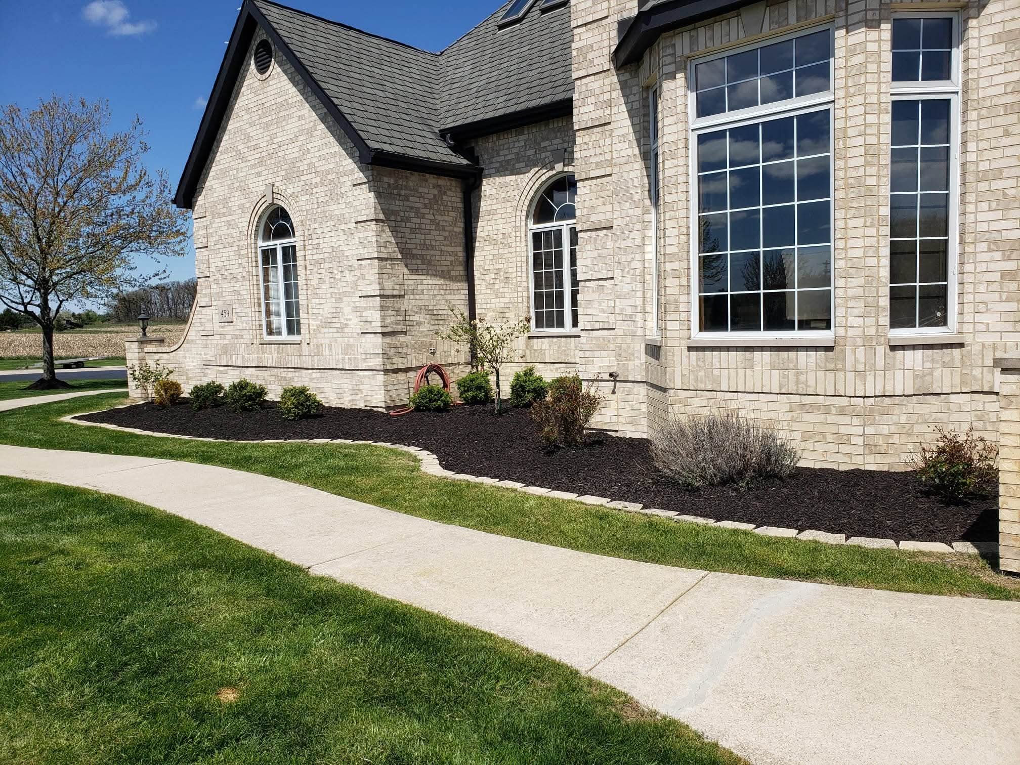 After: the finished mulch bed with stone edging along the brick house