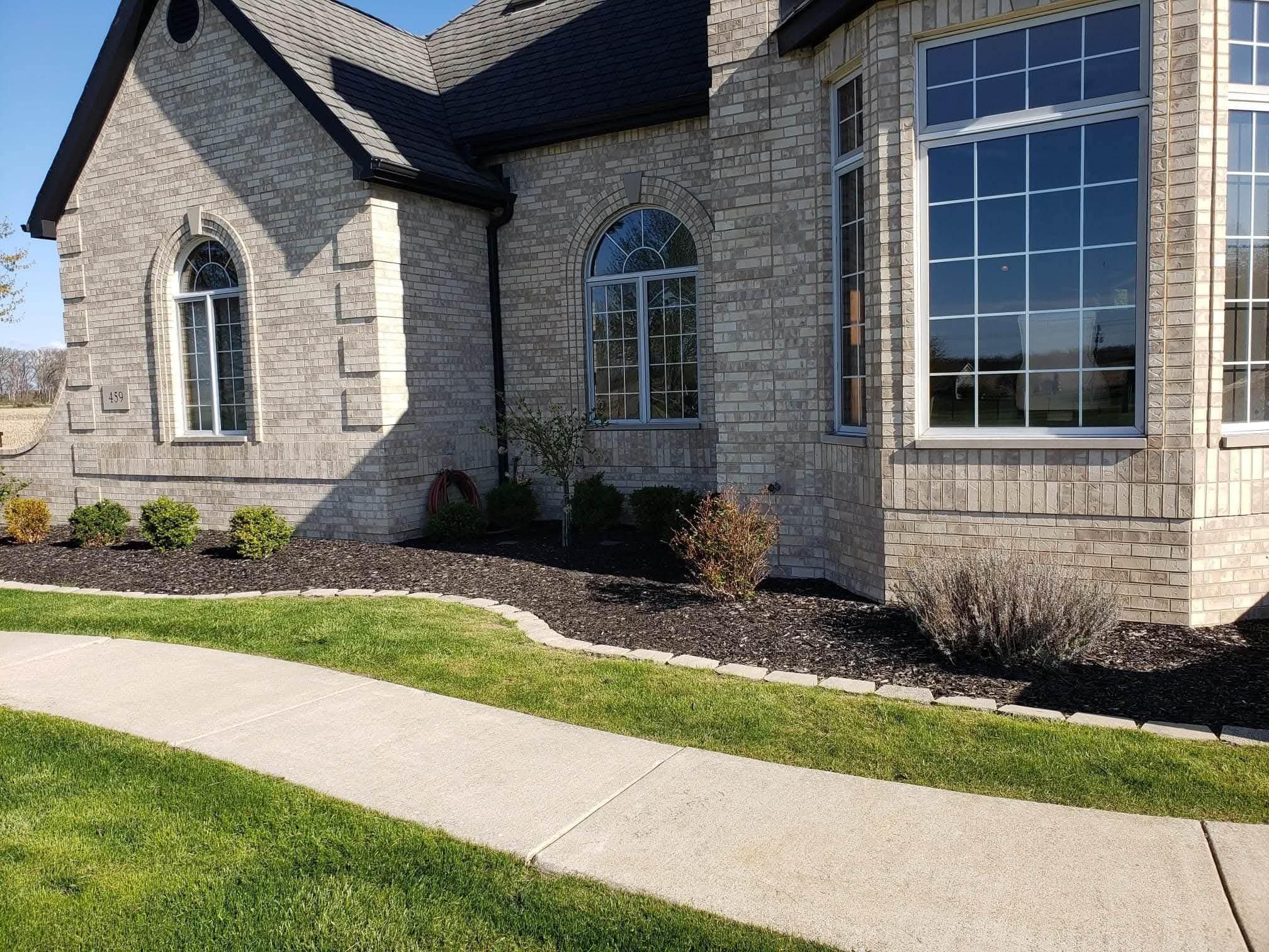 Fresh mulch beds with stone edging along a brick house