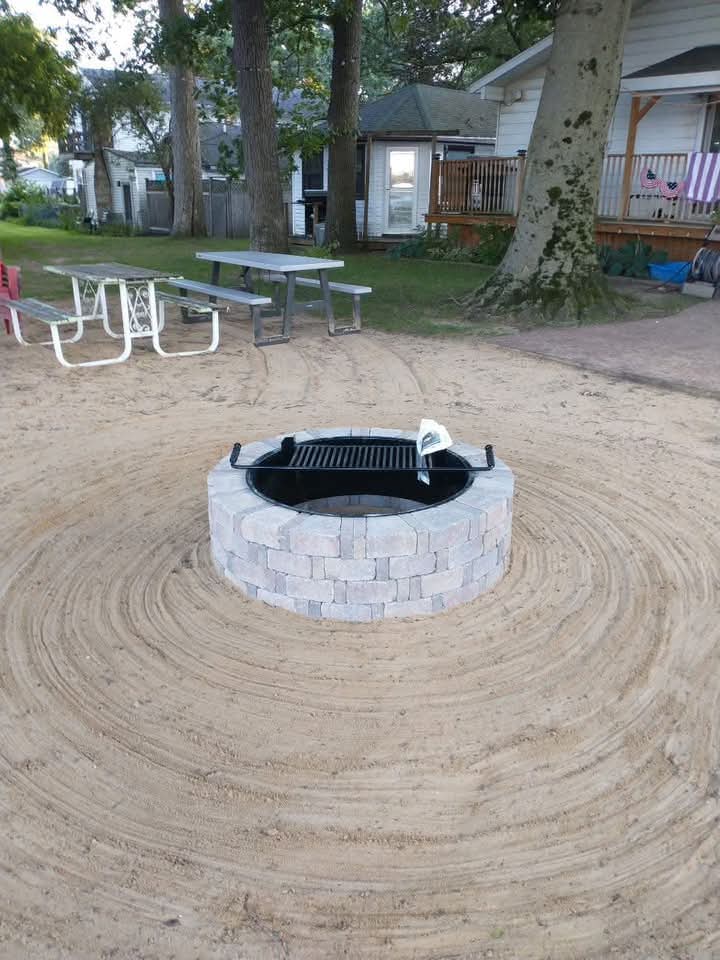 Block fire pit with a cooking grate in a raked sand circle