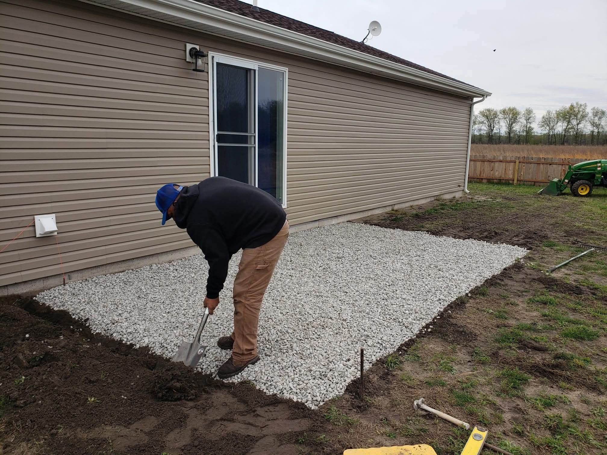 Prepping a gravel patio base behind a house