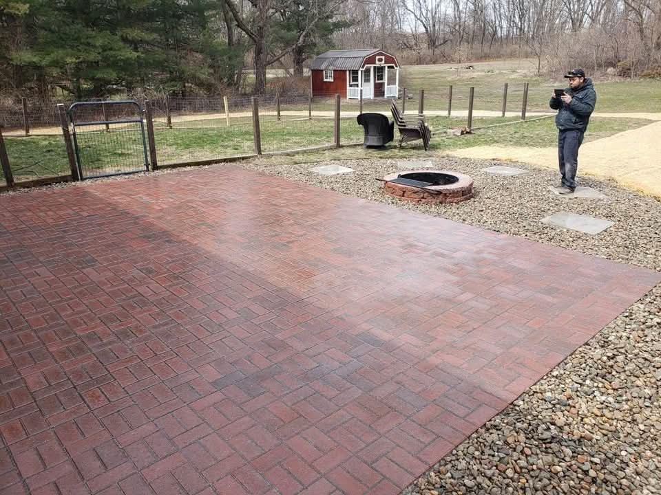 Red brick-paver patio with a fire pit and river rock